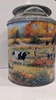 Side view of the tin milk can showing a pasture with cows and autumn trees in the background