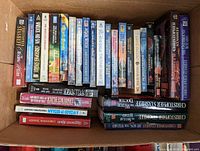 Photo of a large collection of Christopher Stasheff Warlock series sci-fi books stacked in a box, showing spines and covers of multiple volumes.