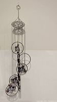 Full view of the cow-themed metal wind chime hanging against a white wall, showing multiple hanging rings and small cow figurines.