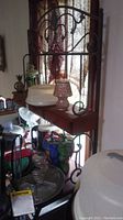 Photo of the bakers rack showing the wood and wrought iron frame with various decorative and kitchen items arranged on shelves and surrounding surfaces.