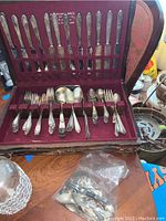 Complete view of the flatware set in fitted red velvet-lined case showing knives, forks, spoons, and serving pieces.