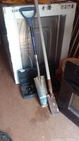 Full lot photo showing hydraulic jack, two garden spades leaning against a dryer and near a heater.