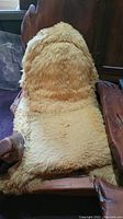 Front angle of redwood chair with cream sheepskin seat cover, showing overall shape and material.