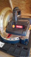 Close-up of Ryobi miter saw blade area and handle with visible Ryobi logo