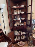 Wood cabinet housing multiple dishware items including plates, bowls, cups with some Japanese stoneware are visible.
