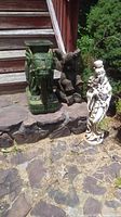 Photo of all three yard ornaments: a green ceramic elephant stool, a concrete elephant statue, and a white goddess statue together on a stone surface outdoors.