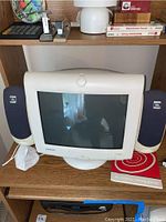 Compaq CRT monitor centered between two JBL black speakers on either side, placed on computer desk shelf
