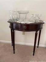 Full view of the dark wood demilune side table with single drawer, showing contents on top (not included).