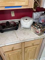 Countertop with the three items arranged side by side: George Foreman mini roaster on right, boxed Black & Decker HandyChopper on far right, Chefman electric skillet on left