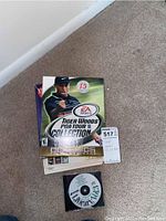 Photo of Tiger Woods PGA Tour Golf Collection box with visible game disc missing, includes instruction manuals and inserts spread out.