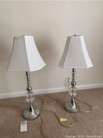 Pair of lamps side by side with octagonal white fabric shades and chrome bases featuring glass orbs, cords attached.
