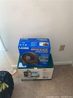 Boxes of a Lasko Breeze Machine fan and a Duracraft DH-904 humidifier stacked together against a wall.