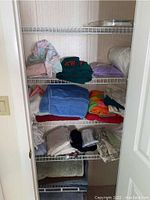 Image of closet shelving containing multiple folded bedding sheets, towels, and linens in pastel and bright colors, assorted sizes.