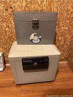 Sentry insulated filing device 1170 placed below the smaller Port-a-File metal box against a wooden background showing overall condition and size comparison