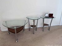 Set of three tables against wall, showing their shape and material details