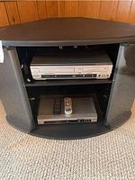 Photo showing two devices stacked in a black media stand, Sylvania video cassette/DVD recorder on top and Panasonic DVD player below.