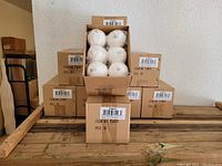Stack of sealed cardboard boxes labeled with item number and quantity containing Christmas ornaments.