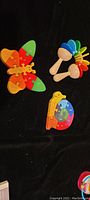 Butterfly-shaped wooden puzzle pieces alongside the organic wood rattle with colorful petals and the snail puzzle partially shown.