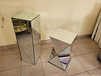 Two mirrored decorative pillars, one tall rectangular, one shorter geometric shape.
