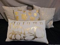 Four autumn-themed throw pillows grouped together showing gold metallic detailing and design variety