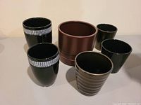 Photo showing 6 dark coloured ceramic planters including black planters with rhinestones, brown planter with saucer, and various textures.