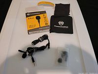 Complete lot with PowerDeWise lavalier microphone, cords, rotating clip, extra foam covers, carrying pouch, and box on white surface.