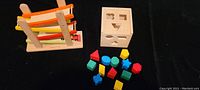 EverEarth wooden ramp racer with two orange and yellow wooden cars, and organic wood shape sorting cube with various colorful blocks on black background.