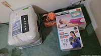 Wide view of lot showing bed-in-a-bag set, two boxed neck massagers, and body shower gift set