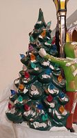 Close-up of vintage ceramic Christmas tree with multicolored light bulbs and painted snow accents