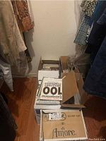 Photo of five large boxes filled with assorted magazines stacked in closet space with wood flooring.