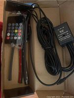 Photo of remote control and one LED light strip with wires and IR music controller box inside a cardboard box.