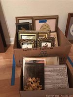 Box containing multiple assorted framed prints and plaques of varying sizes from small 4x3 to larger 12x10 inches with diverse frames and styles.