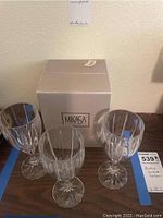 Three Mikasa Berkeley wine glasses displayed with original Mikasa box behind them on a wooden surface.