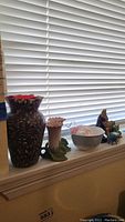 Full view of lined-up lot items on windowsill including vases, candleholders, bowl, and figurines.