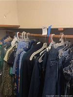 Photo showing assorted women's clothes hanging on a clothing rod including various shirts, jackets, and denim items mainly in size 7/8.