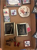 Photo showing the two religious framed wall plaques and various colorful refrigerator magnets including butterflies, flowers, a teddy bear, and Texas symbol.