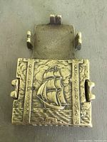 Close-up of the closed brass case top showing detailed sailing ship embossed design and rivet details.