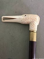 Close-up side view of carved bird head handle showing open beak and carved feather texture