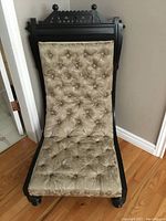 Front view of carved crest rail with finials and full tufted seat and back