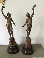 Front view of pair of antique metal figural statues on their bases.