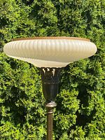 Close up of white ribbed glass shade with brown tortoise shell style rim and bronze tone decorative holder with eagle motif