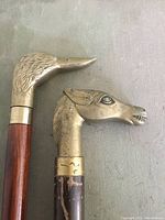 Close-up of brass duck head and horse head handles on wooden shafts.