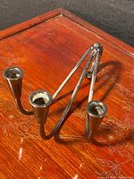Close-up image of one silver-plated tri-candle Danish candlestick showing the tubular structure and candle holders.