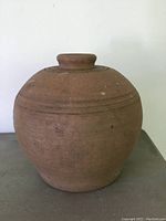 Front side view of the round stoneware vase showing horizontal ring details and surface wear marks.
