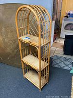 Full view of the bamboo shelf with three woven shelves and curved top.