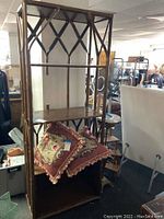 Full view of bamboo shelf showing three shelves with a mirror back and bamboo frame. Two decorative pillows are on the bottom shelf to show scale.