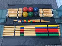 Full view of contents laid out in black carrying case showing bocce balls, pallino balls, wooden spoons, and wooden stakes
