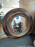 Front view of the distressed round wall mirror showing the large circular glass and thick wooden frame with visible wear and scuffs.
