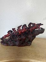 Front angled view of red horse sculpture depicting seven horses on a rocky base.