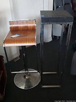 Bar stool and tall side table placed next to each other, showing overall forms and materials.